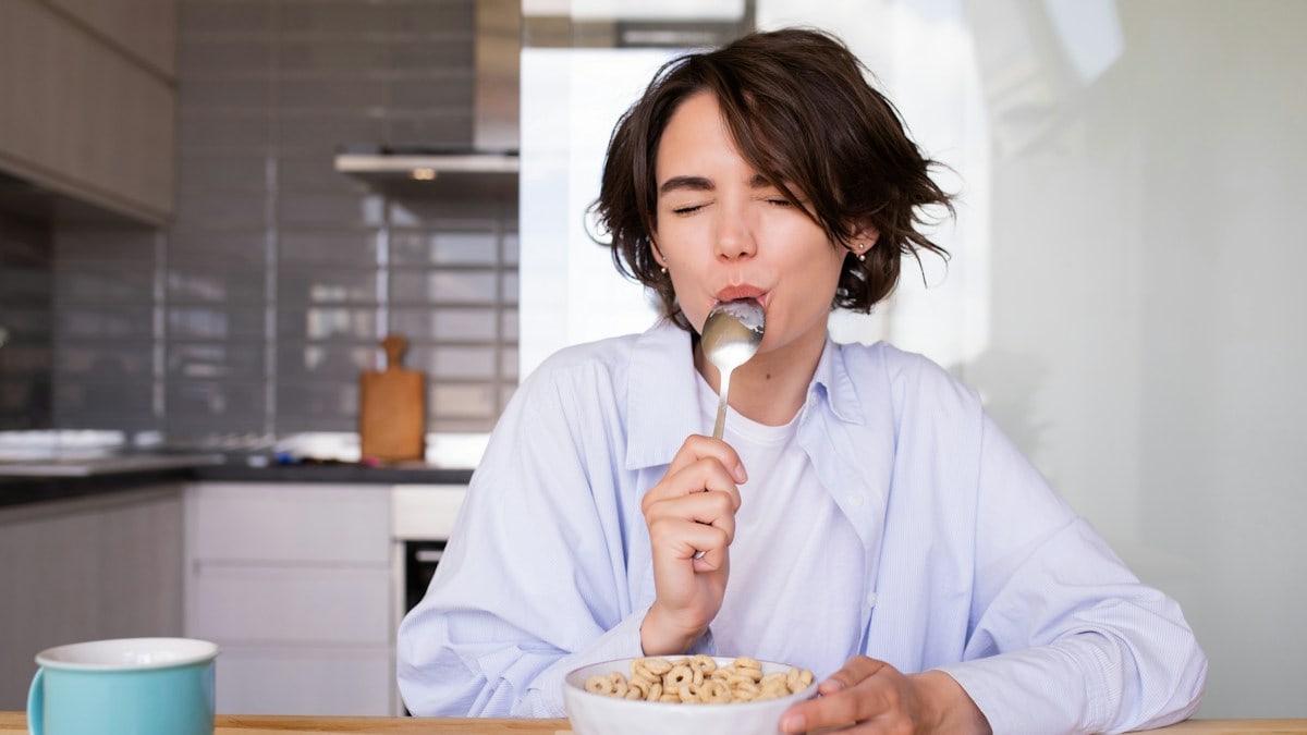 a woman eating cereal from a bowl with a spoon